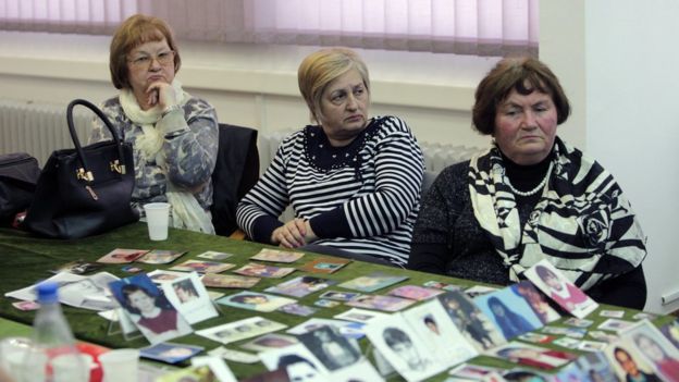 Sarajevo women watch the reading of the verdict as victims' pictures are displayed on a table - 24 March