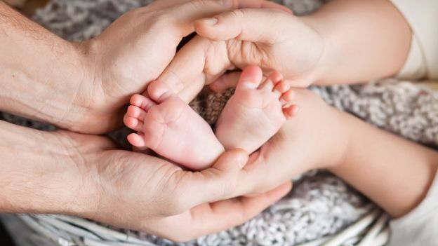 Mãos envolvendo pés de bebê