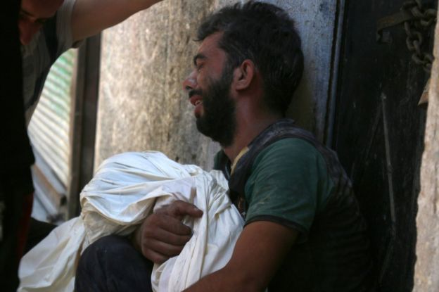 A Syrian man mourns a dead child after a reported air strike in the rebel-held Saleheen district of Aleppo on 16 July 2016