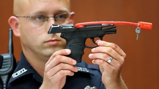 Sanford police officer Timothy Smith holds up the gun that was used to kill Trayvon Martin - June 2013