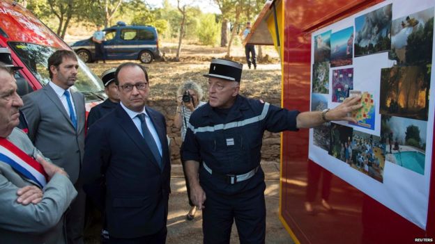 France's President Francois Hollande (C) listens during a visit with fire fighters in Bormes-les-Mimosas