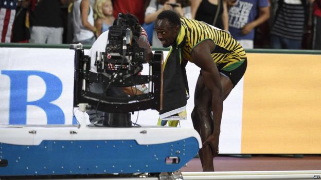 Usain Bolt rubs his ankle after falling in Beijing, China (27 Aug 2015)