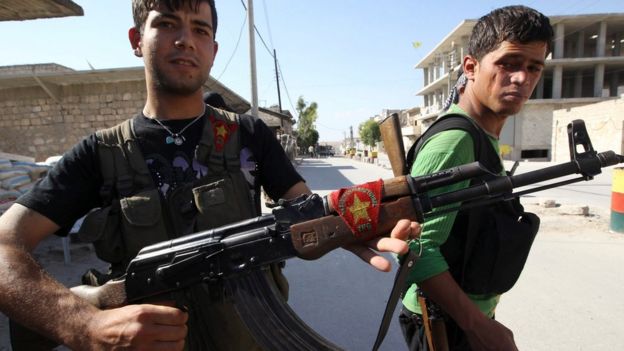File photo: A Kurdish fighter from the Popular Protection Units (YPG) shows his weapon decorated with his party's flag, as a fellow fighter looks on in Aleppo's Sheikh Maqsoud neighbourhood, 7 June 2013