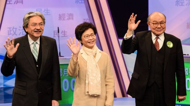 Hong Kong's three leadership candidates (L-R) John Tsang, Carrie Lam and ex-judge Woo Kwok-hing wave as they arrive at a studio before facing off in their first televised debate in Hong Kong on March 14, 2017.