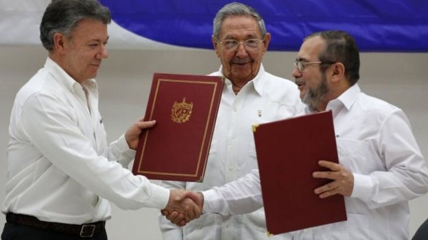 Colombian President Juan Manuel Santos, left, and Commander of Farc, Timoleon Jimenez, right, shake hands during a signing ceremony of a ceasefire and rebel disarmament deal, in Havana, Cuba.