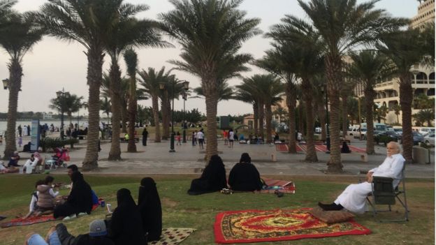 Saudis relax on outdoors, sat on the grass beneath trees