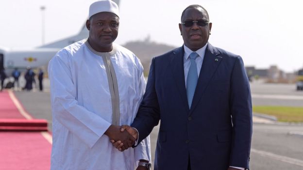 Senegal's President Macky Sall (R) shakes hands with Adama Barrow prior to leaving the Senegalese capital Dakar for The Gambia on January 26, 2017