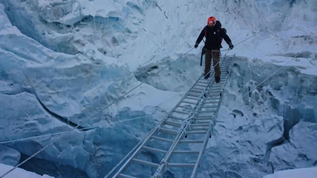 Photo of a man crossing a crevasse on the way to the summit of Mount Everest