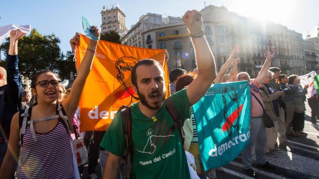 Protesters with 'democracy' flags chant outside the Catalan economy ministry