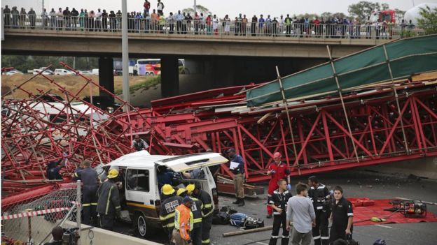 Paramedics try to free passengers trapped in a taxi after a bridge collapsed on the M1 highway