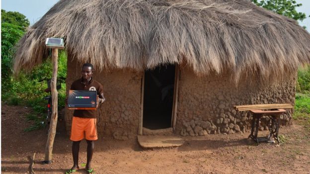 Man with laptop beside solar panel