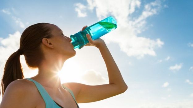 Mulher bebe água após exercício físico