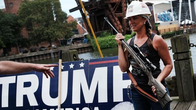 Una mujer que apoya a Trump sostiene un arma larga.