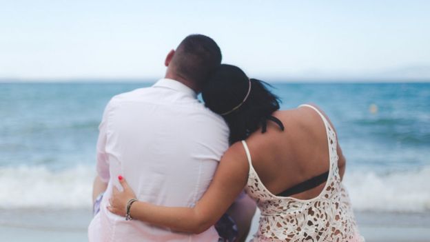 A couple hugging and looking out to sea