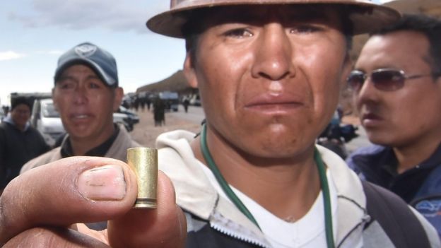 A Bolivian miner shows a bullet shell that was used to kill one of the two dead miners