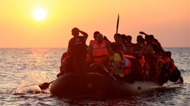 Migrants paddling a rubber dinghy close to the beach