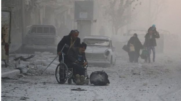 A man on a wheelchair flees with others into the remaining rebel-held areas of Aleppo, Syria on 9 December 2016