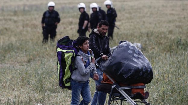 Migrants carry their belongings as they leave Idomeni camp, Greece, on 24 May 2016