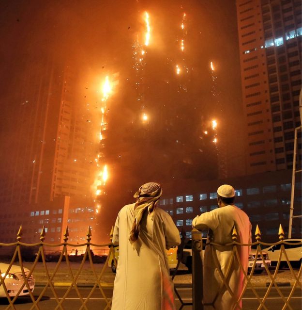 Two Emirati officials as a fire spreads up the side of the watch a high-rise building in Ajman, United Arab Emirates, early Tuesday, March 29, 2016