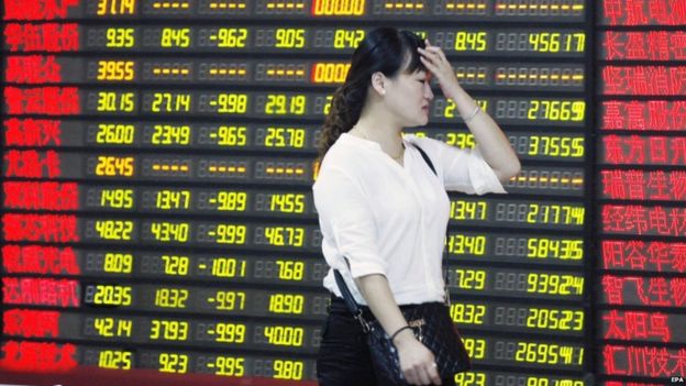 A stock investor walks by a screen at a brokerage house in Huaibei, Anhui province, China, 24 August 2015. China