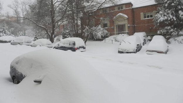 A photo taken on January 23, 2016 shows snow-covered cars on a residential street in the northwest of Washington, DC.