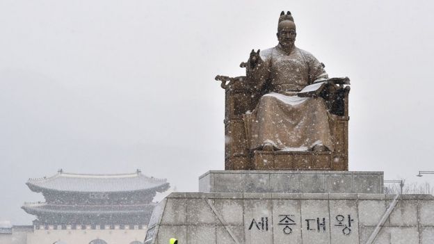 A bronze statue of King Sejong during snowfall in Seoul.