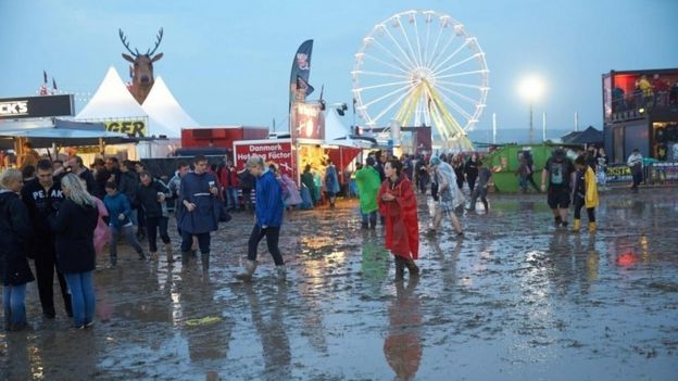 Visitors to the Rock am Ring music festival wade through mud after a heavy downpour (04 June 2016)