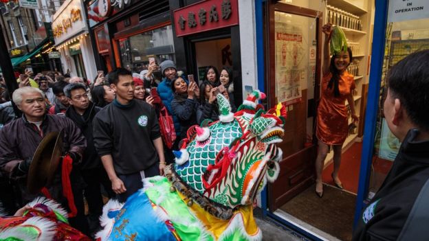 Performers in costume receive offerings from local businesses in Chinatown during the Chinese New Year celebrations