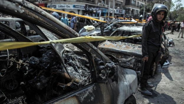 Egyptian policeman stands beside a car destroyed in a bombing that killed Prosecutor General Hisham Barakat (29 June 2015)