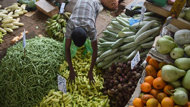 A Sri Lankan stallholder arranges vegetables at a market in Colombo