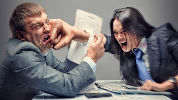 Business woman punching another businessman