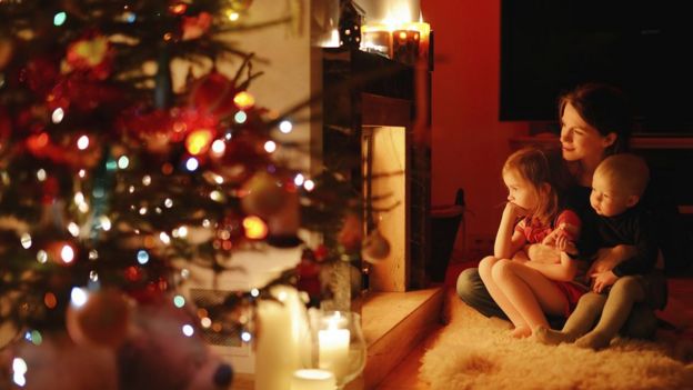 Mother with two young children by Christmas tree