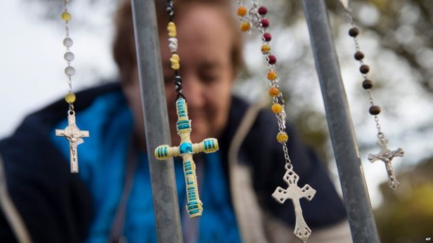 Lupe Cantu, of McAllen Valley, Texas, hangs rosary beads on a barricade along Benjamin Franklin Parkway as she waits for Mass delivered by Pope Francis, Sunday, Sept. 27, 2015, in Philadelphia