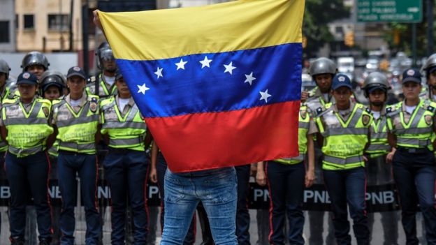 Un manifestante con la bandera de Venezuela frente a la policía