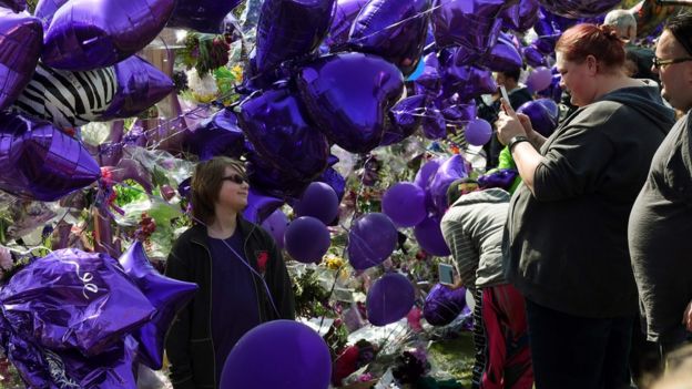 Prince fans pose for photos amongst a sea of purple balloons outside the Paisley Park compound in Minneapolis