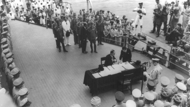 Japanese Foreign Minister Mamoru Shigemitsu (seated) signs the surrender document aboard the USS Missouri