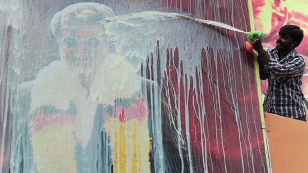 An Indian fan pours milk on a hoarding of Indian movie star, Rajinikanth erected in front of a movie theatre, ahead of the release of his Tamil movie 