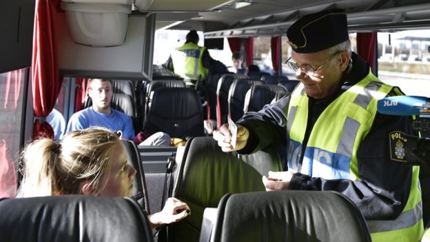 A police officer checks the documents a a passenger inside a bus at Lernacken on the Swedish side of the Oresund strait on 12 November 2015.