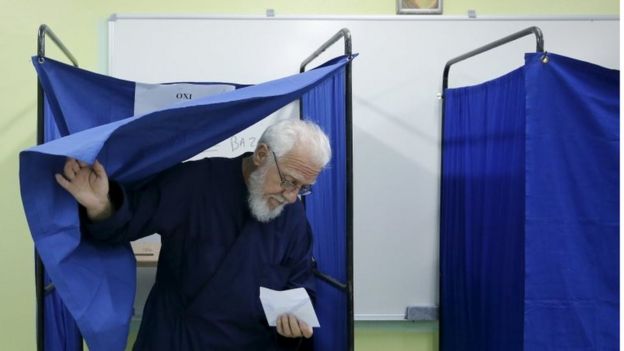 A Greek Orthodox priest exits a voting booth holding his ballot at a station in Athens on 20 September 2015