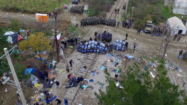 In this aerial photo taken from a drone, Macedonian policemen use their shields to take cover during clashes with migrants at the Greek-Macedonian border near the northern Greek village of Idomeni, on Saturday, Nov. 28, 2015.