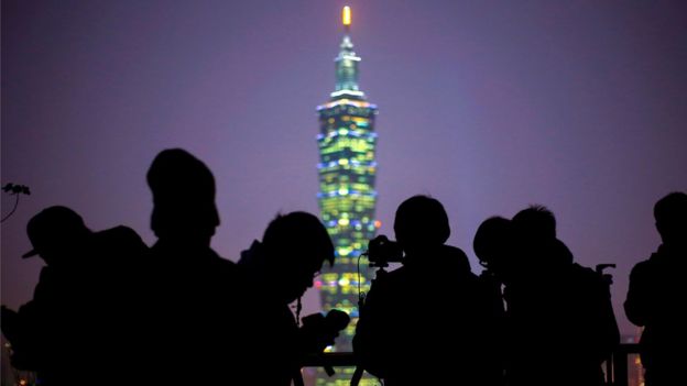 Photographers prepare to take photos of fireworks go off at the Taipei 101 skyscraper on New Year