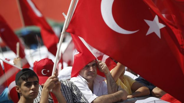 Miting alanında toplanan kalabalık ellerinde Türk bayraklarıyla bekliyor.