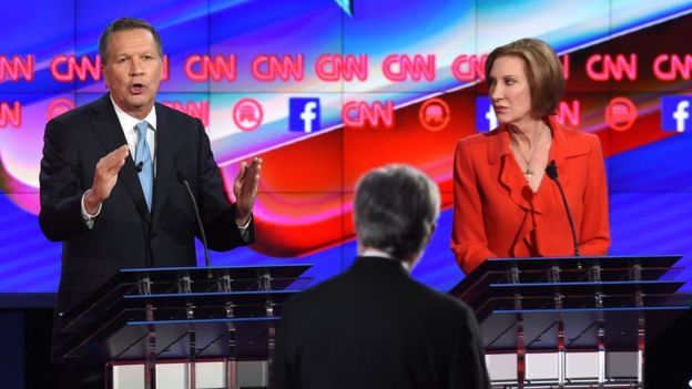 Republican presidential candidate Ohio Governor John Kasich (L) speaks as businesswoman Carly Fiorina looks on during the Republican Presidential Debate, hosted by CNN