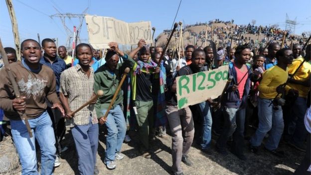 Miners demonstrate at a mountain close to the mine near Rustenburg where they are demanding that their wages are more than tripled on 16 August 2012