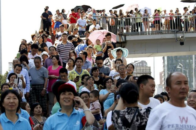 People watch military helicopters on a pedestrian overpass outside the closed area during the military parade to mark the 70th anniversary of the end of World War Two, in Beijing, China, 3 September 2015