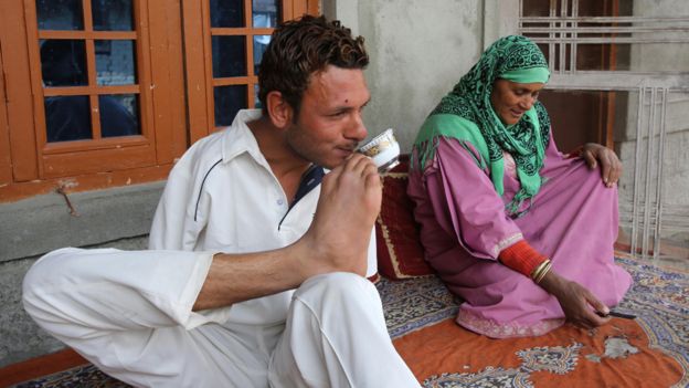 Amir drinks a cup of tea - he holds the cup in his foot