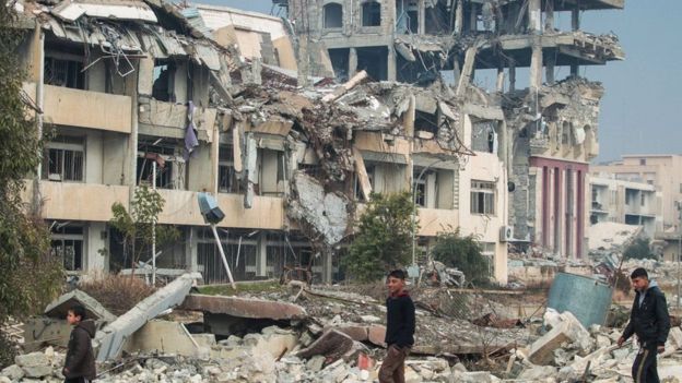 прохожие на фоне разрушенного здания