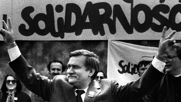 Solidarity founding leader Lech Walesa shows v-sign in front of Solidarity poster during his presidential campaign in Plock (7 May 1989)