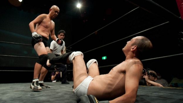 Shintaro on the floor with the referee and Kitajima standing over him