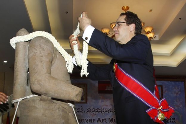 Denver Art Museum Director Christoph Heinrich decorates a bundle of jasmine to the Torso of Rama, a 10th century stone statue, during a handing over ceremony in Phnom Penh, Cambodia, Monday, 28 March 2016